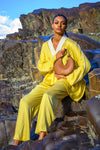 Person in a yellow outfit holding a brown linearity bag against a rocky background