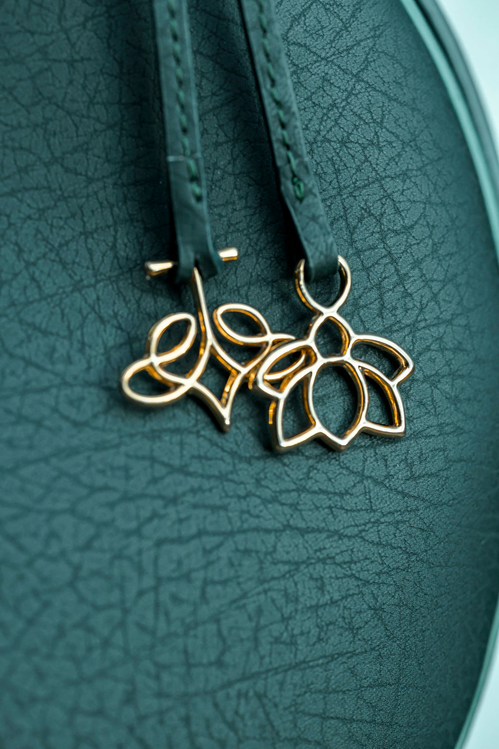 Gold colored charms of linearity on a textured green bag