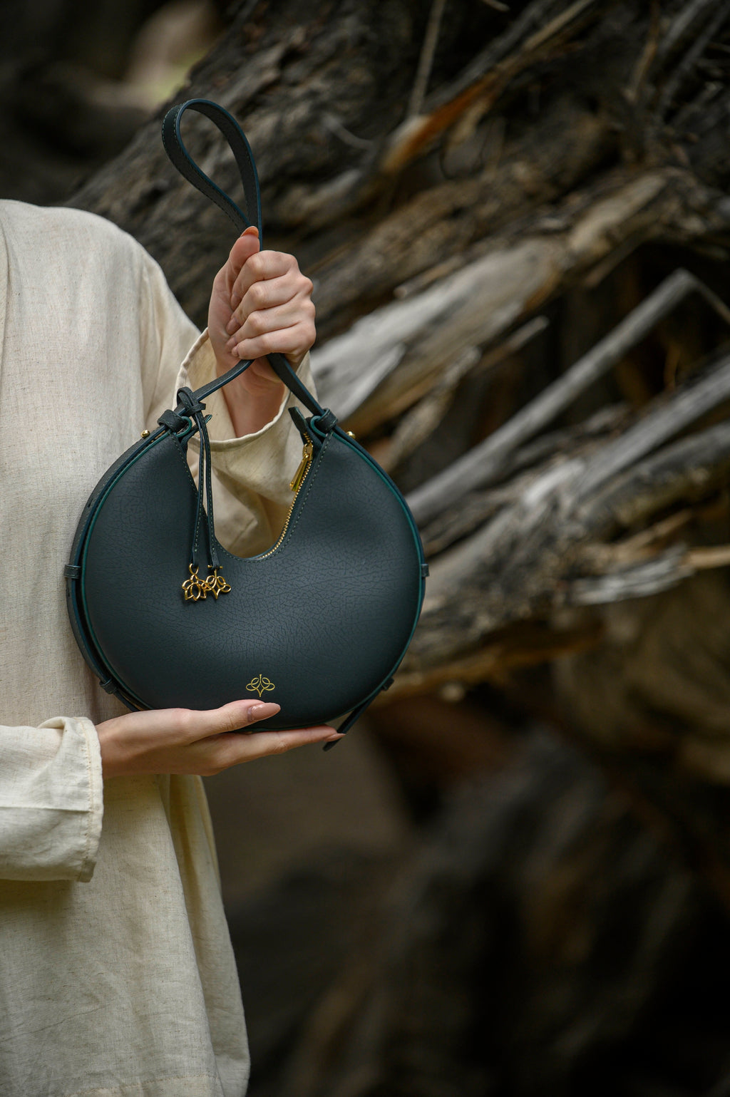 Person holding a green linearity handbag against a rustic wooden background