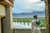 Woman standing on a rooftop with a green linearity bag in a scenic view of mountains and greenery.