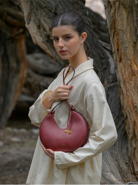Model holding a burgundy Linearity bag