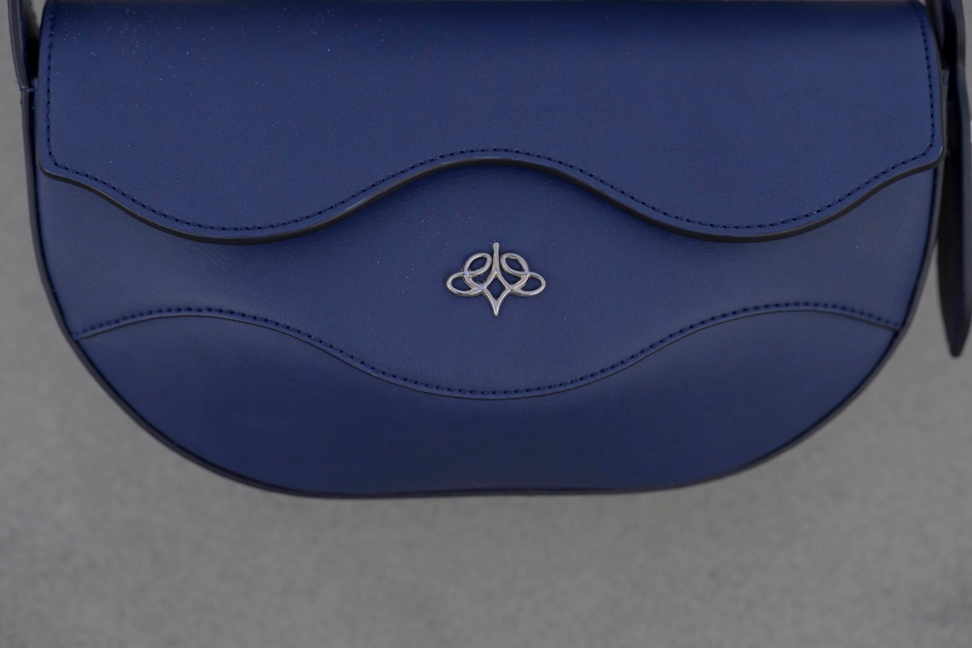 Blue handbag with linearity logo on a sandy background