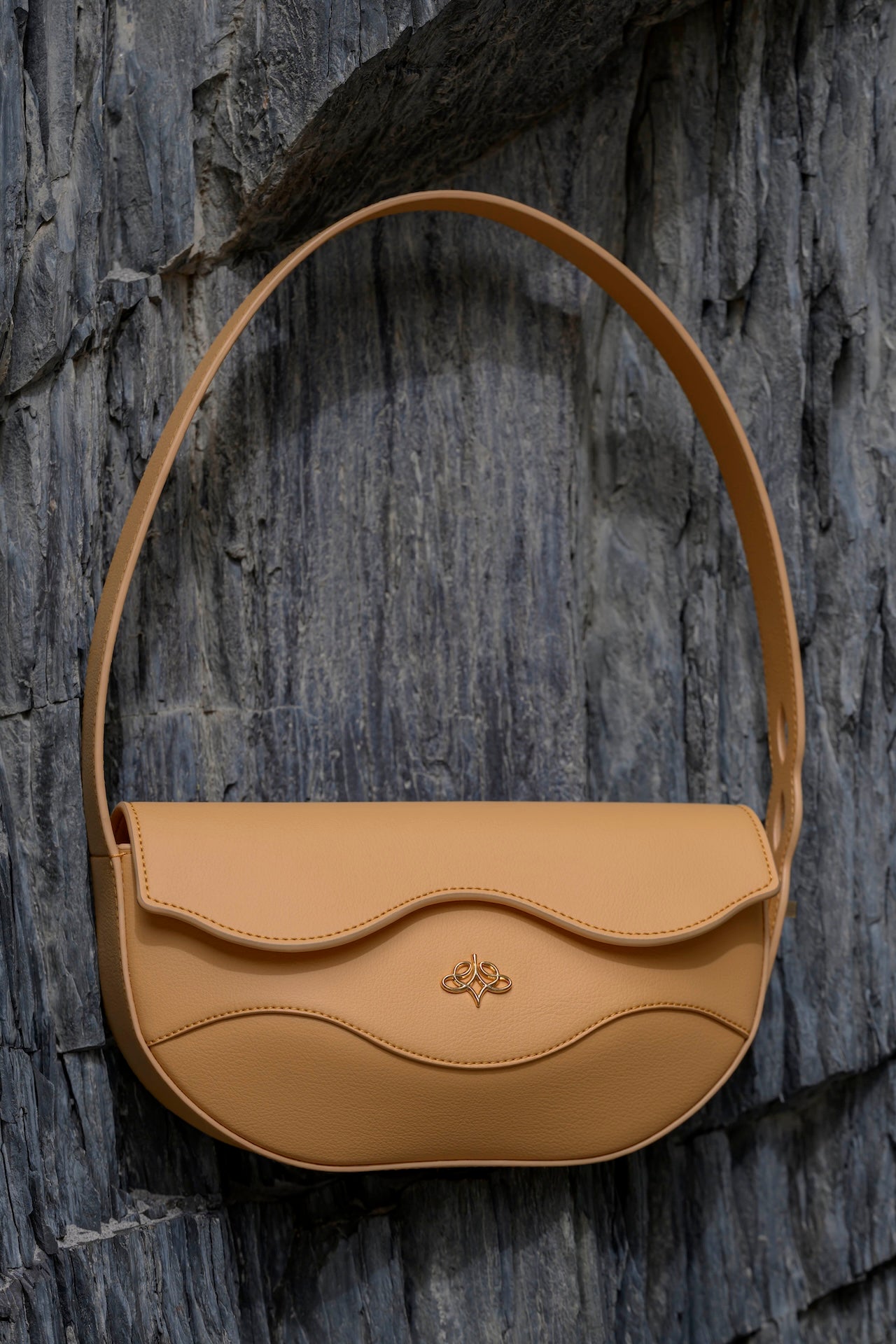 Beige handbag with a subtle Linearity logo on a textured stone background