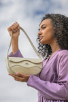 Woman holding a Linearity handbag against a cloudy sky