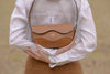Person holding a cognac linearity handbag with a blurred background