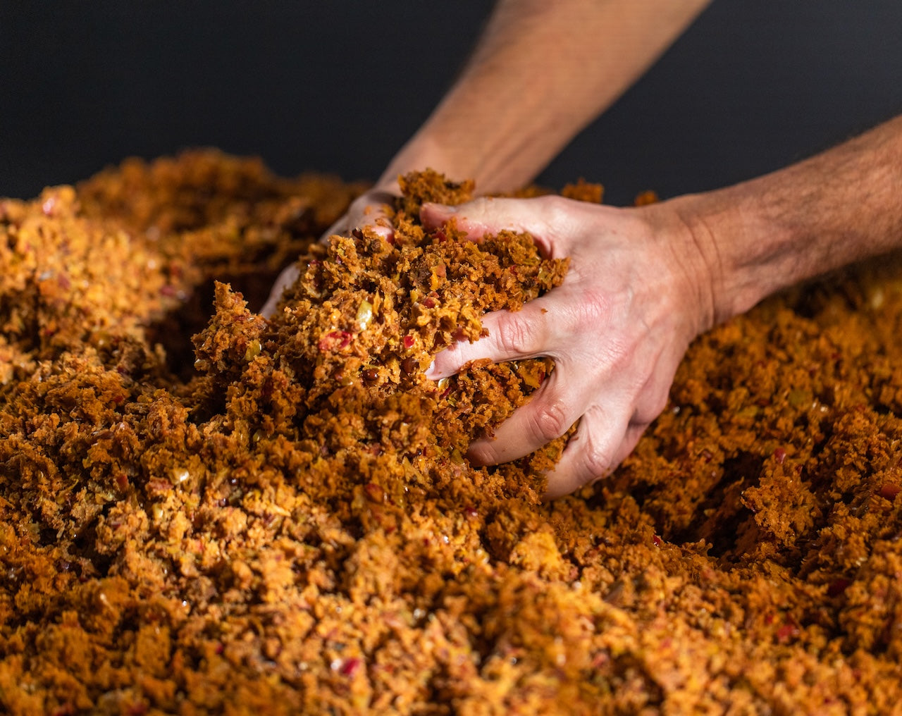 Hands interacting with a pile of Apple waste against a dark background